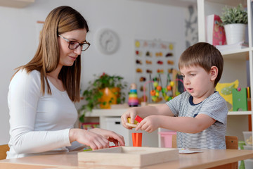 Mother or preschool teacher with cute child playing - education