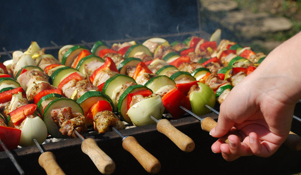 Summer time outdoor oil drum barbecue with shish skewers of chicken and vegetables in the garden