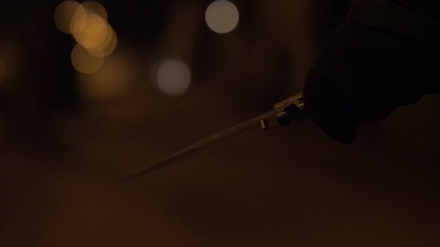 A knife in a hand of a woman. Night street slow motion