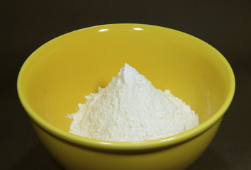 Pure white dry flour in a yellow ceramic bowl 