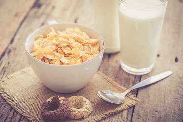 milk, cookies and bowl of cereal on wooden background