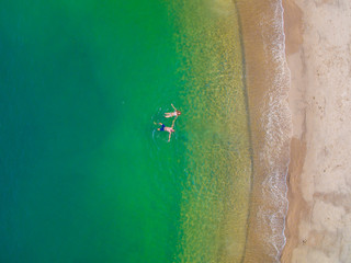Man and woman sunbathing and swimming on the shore of the turquoise sea