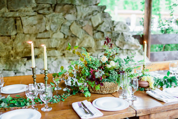 Wedding decor for banquet. Table setting with dishes, cutlery, candle and floristic.