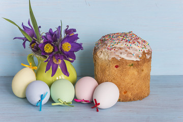 easter concept/easter cake,painted eggs and bouquet of eastern pasqueflowers on blue woodenb...