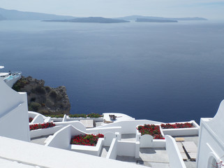 Stunning View of Blue Aegean Sea and White Terrace with Red Flowers, Santorini Island of Greece  