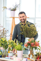Florist at work: the young MAN making fashion modern bouquet of different flowers