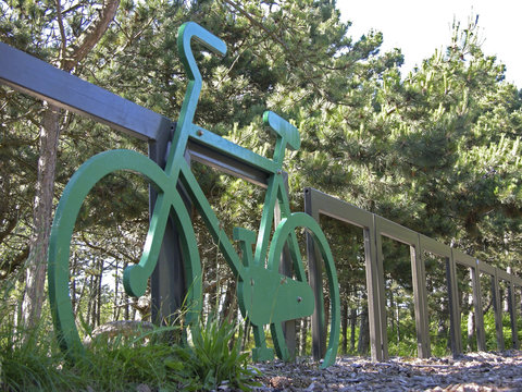 A green bicycle against a fence in the woods.