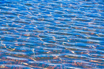 The water in the pool has a tile bottom tile glittering in the sun. Background, texture