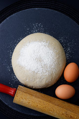 Homemade organic Dough whit rolling pin and eggs for bake pizza or bread on black slate stone plate 