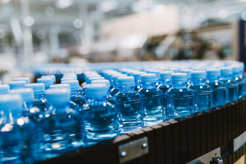 Water factory - Water bottling line for processing and bottling pure spring water into small blue bottles. Selective focus.