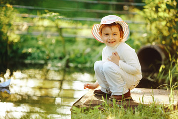 girl plays with paper boat in the river