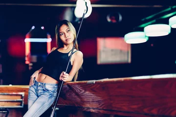 Poster Young beautiful girl in a billiard club, with cue stick posing © Ivan Trizlic