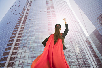 Obraz na płótnie Canvas triumphantly beautiful young woman business leader is dressed in Superman's Cape