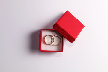 Gold wedding rings in a red box on a white background