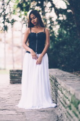 Fototapeta na wymiar Beautiful girl in long white dress, posing in the park