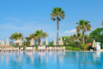 outdoor swimming pool, palm trees and a cozy area for sunbathing
