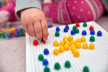 toddler plays with colorful pins