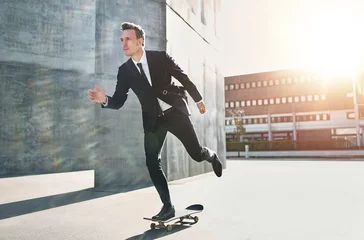 Poster Confident skater wearing suit riding in city © Flamingo Images