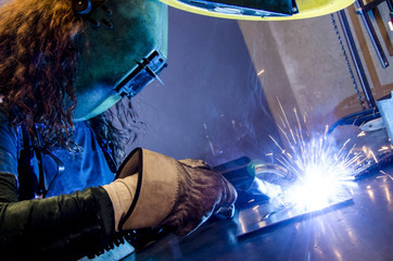 Woman welding in the metal industry - obrazy, fototapety, plakaty