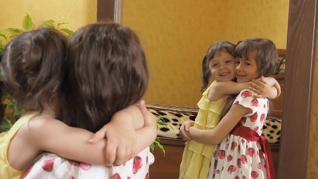 Children in front of the mirror. Sisters are hugging. Little girls in front of a mirror.