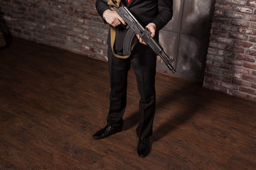 Assassin in suit and red tie holding machine gun