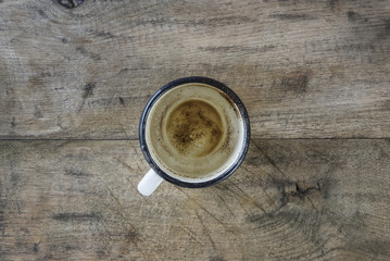 Emptied old metal coffee mug on wooden background