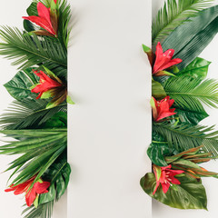 Creative layout made of tropical palm leaves and colorful flowers. Summer concept. Flat lay.