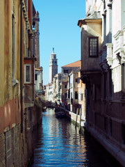 Fototapeta na wymiar Sunlit canal venice on a summers day with blue sky and reflections