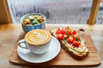Fototapeta na wymiar Hummus and tomato sandwich, salad and fresh hot cappuccino coffee