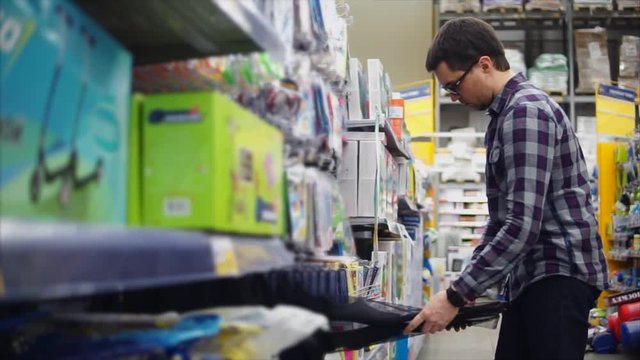 Man in the shopping center choosing goods. Choosing and inspecting the swimming mask for scuba diving. Sports inventory for summer vacation. Concept of shopping in the mall.