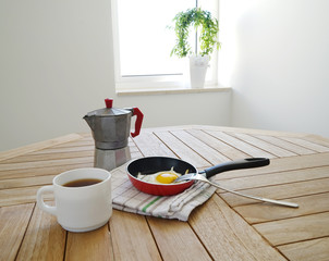 Fried eggs with coffee pot on the table and window background