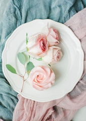 Homemade buttercream cupcakes with roses on a plate and cloth.  Flat lay, top view