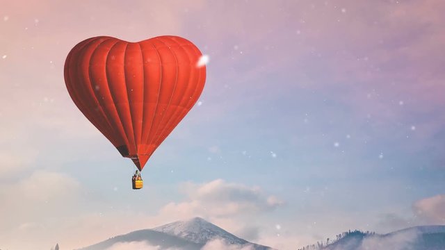 Red hot air balloon heart shape fly in blue and pink pastel sky. Foggy mountains in the background. Romantic journey on Valentine's Day. Travel, holidays, recreation. Nature landscape. Slow motion 4K