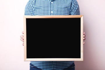 Male hands holding wooden frame on beige background