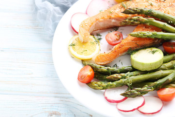 Steak of salmon with asparagus and vegetables on white plate