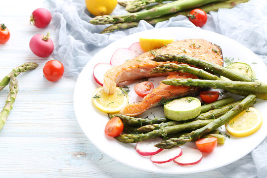 Steak of salmon with asparagus and vegetables on white plate