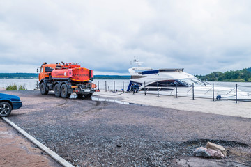 Petrol tanker fills the yacht at the pier on the river