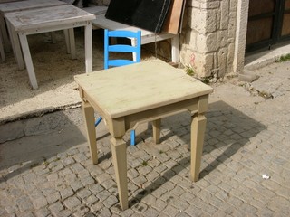 Schöner alter Holztisch in Beige und Naturfarben und Stuhl in Blau im Sommer in den Gassen der...