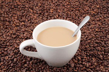 A white coffee cup on a background of whole coffee beans