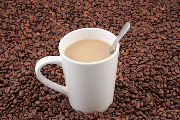 A white coffee cup on a background of whole coffee beans