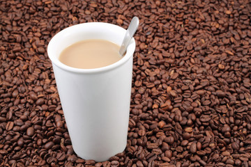 A white coffee cup on a background of whole coffee beans