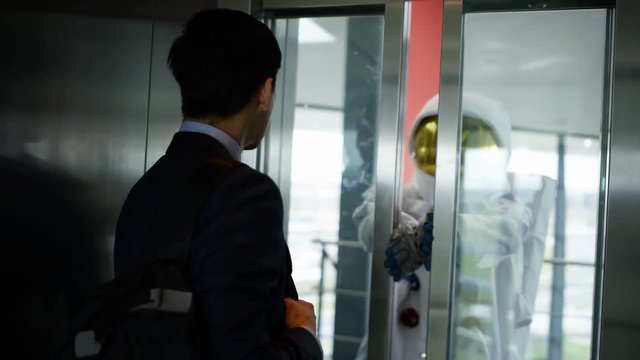  Astronaut taking the elevator with businessman in modern office building