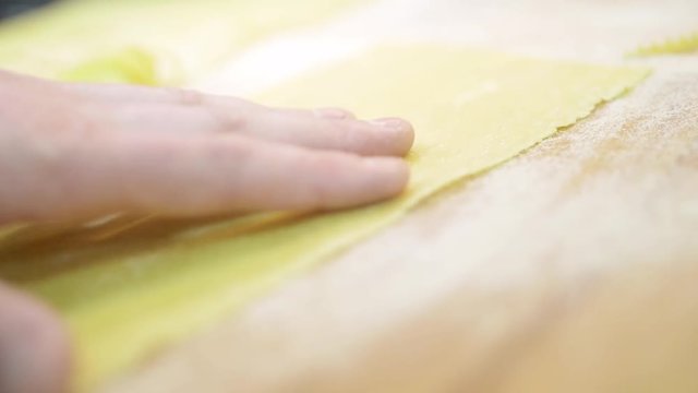 Professional cutting pasta from a sheet of raw dough In a restaurant cafe close-up, slow mo