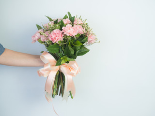 Woman hands holding a flower in green meadow, with focus on a flower. Pink Flower and nice ribbon.Pretty girl in a jeans dress on white background.