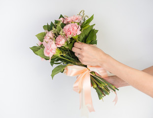 Woman hands holding a flower in green meadow, with focus on a flower. Pink Flower and nice ribbon.Pretty girl in a jeans dress on white background.