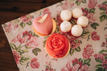 Different cakes on a wooden table and rag napkin in flowers. Red cakes.