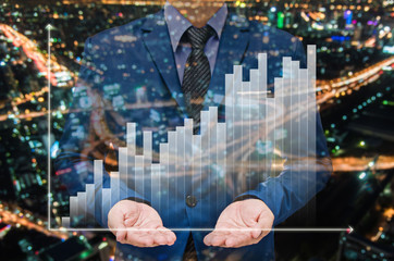 businessman with growing graph on virtual screen and night modern city building background