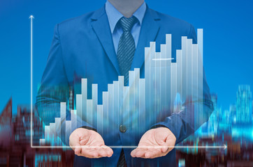 businessman with growing graph on virtual screen and night modern city building background