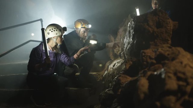  Team of potholers with hard hats and lamps exploring underground cave system