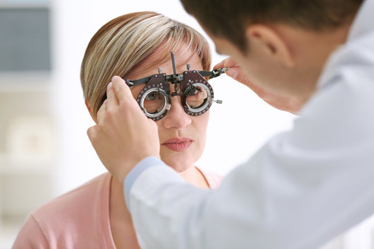 Ophthalmologist examining eyes of mature woman in clinic, closeup